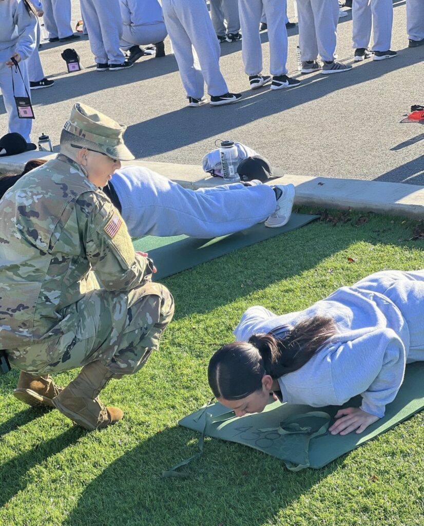 Students doing pushups and being overseen by a staff member.