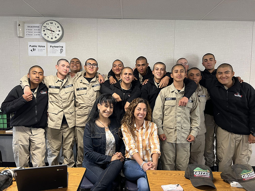 A group of students smiling, several in uniform, at the camera.